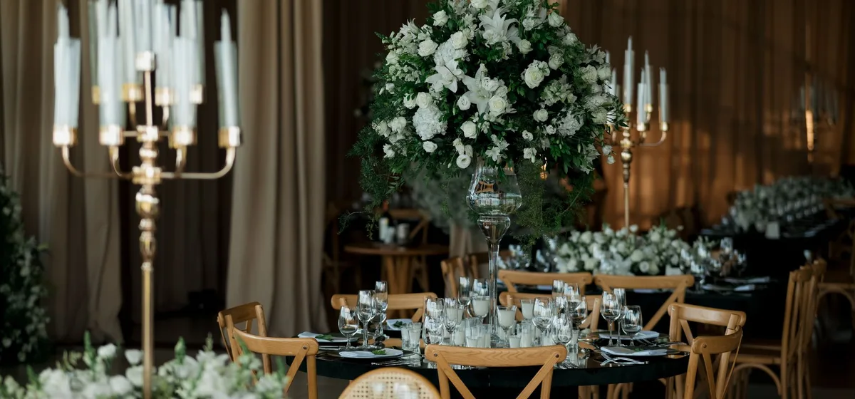 Elegantní výzdoba stolů na svatbě s bílými květinami a svícemi